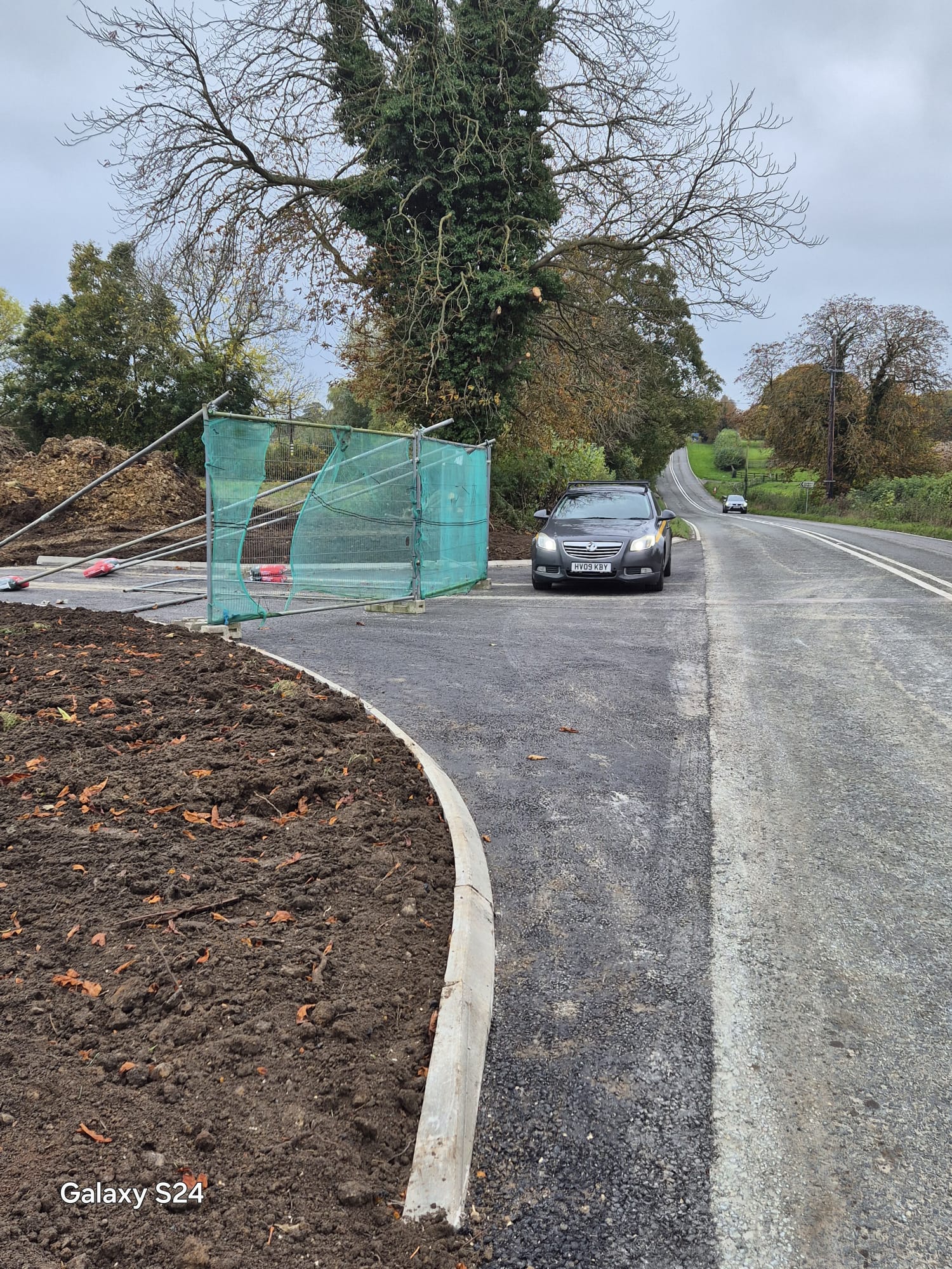 New kerbed site access with fencing and a highway maintenance vehicle pulling onto the carriageway