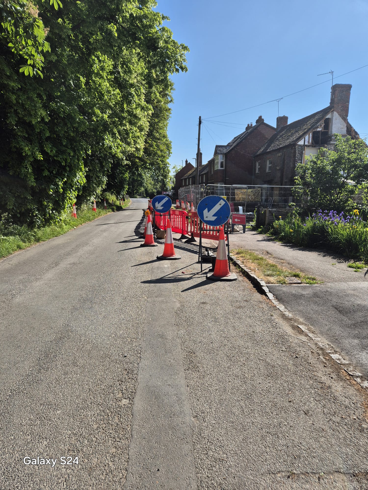 Keep-left arrow signs and barriers closing a street corner beside scaffolding