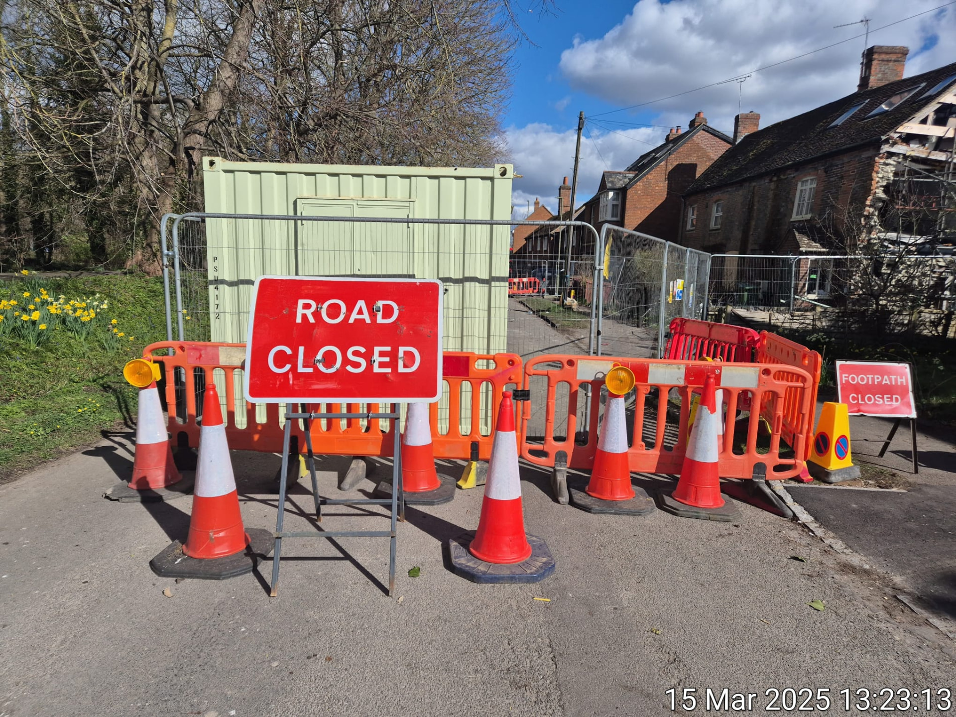 Road closed sign, cones and pedestrian barriers sealing a village street with footpath closed signage in place