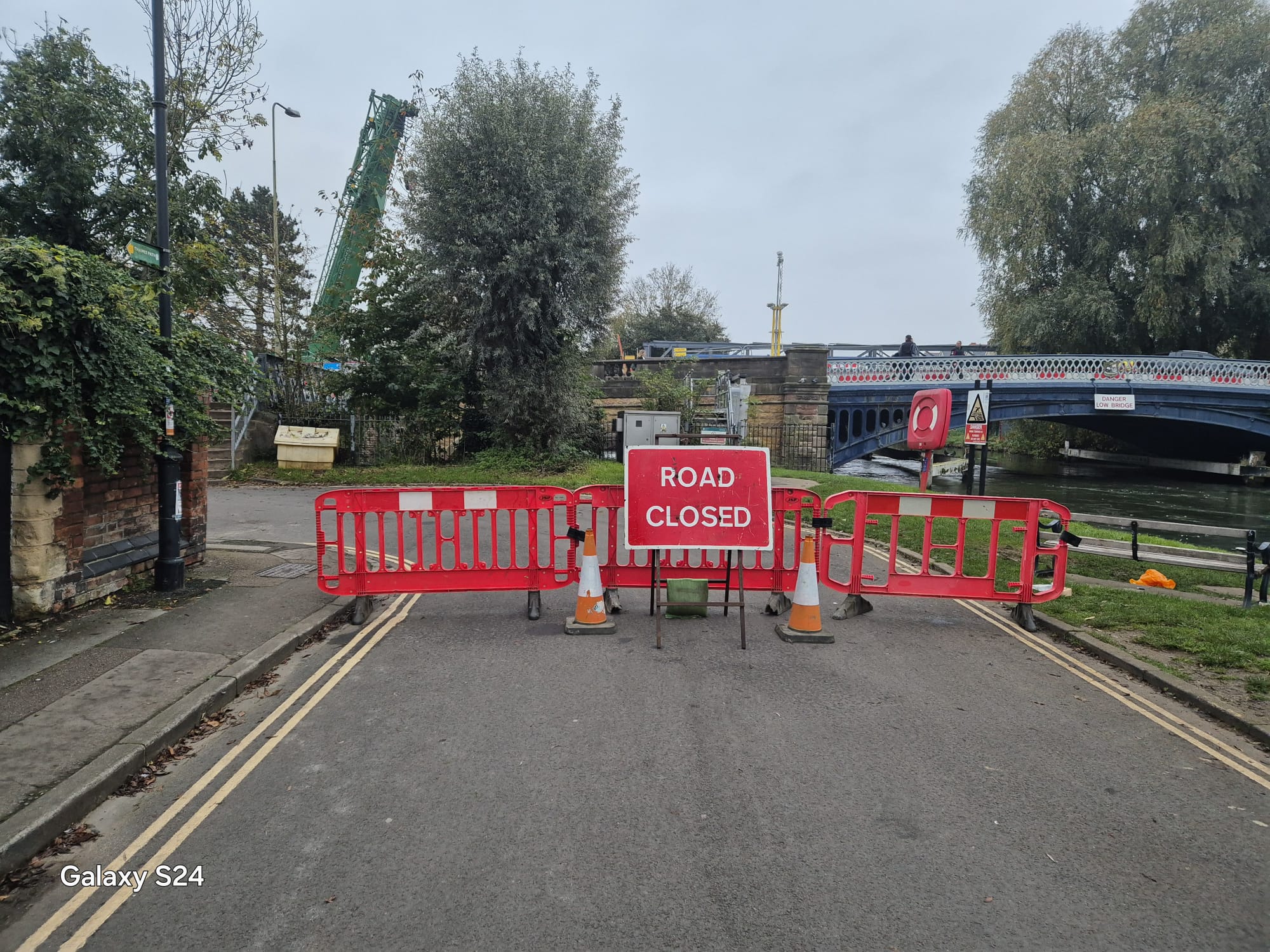 Road closed sign and barriers at the approach to a steel arch bridge