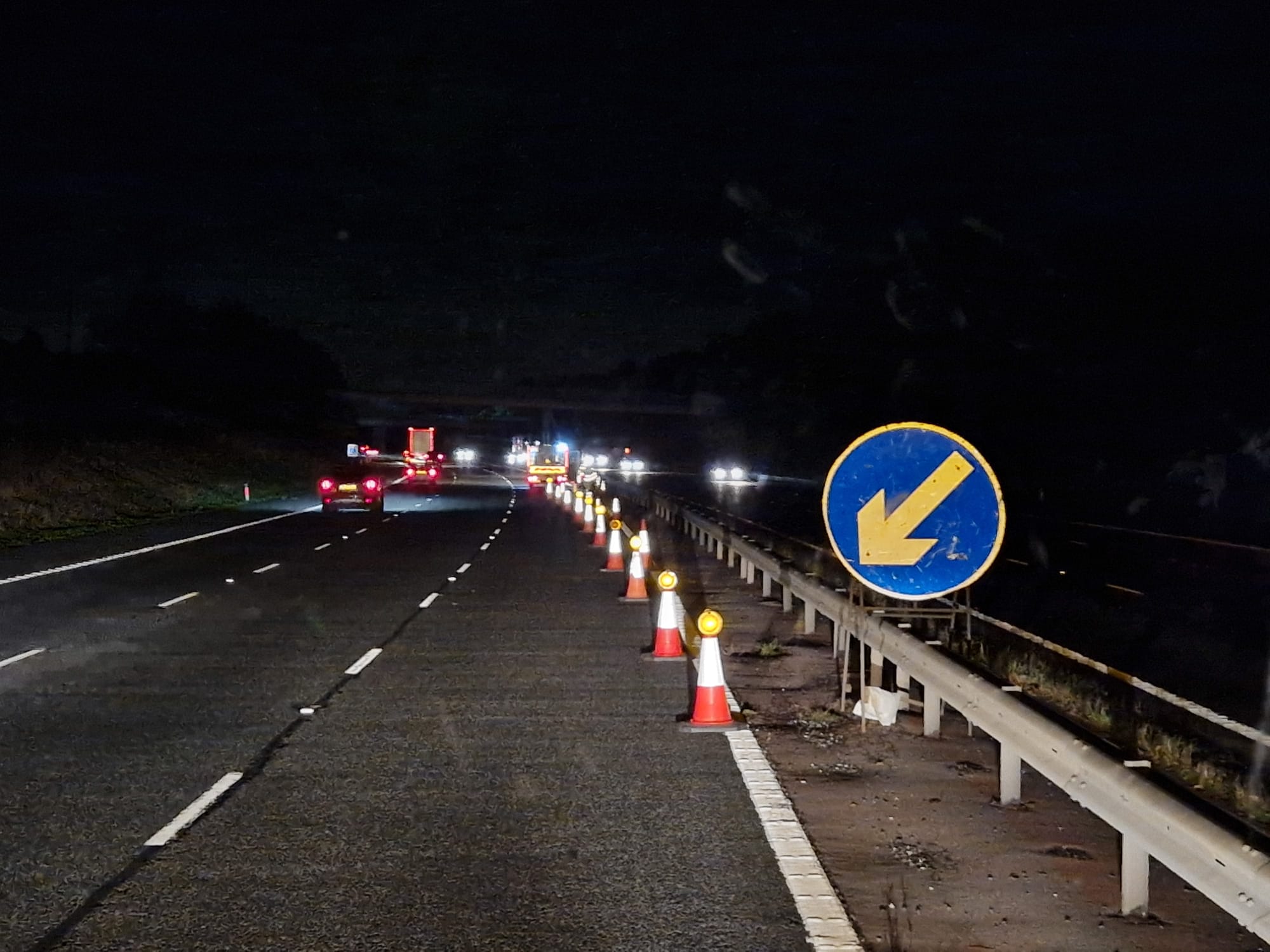 Illuminated cone taper leading to a lane shift arrow sign at night