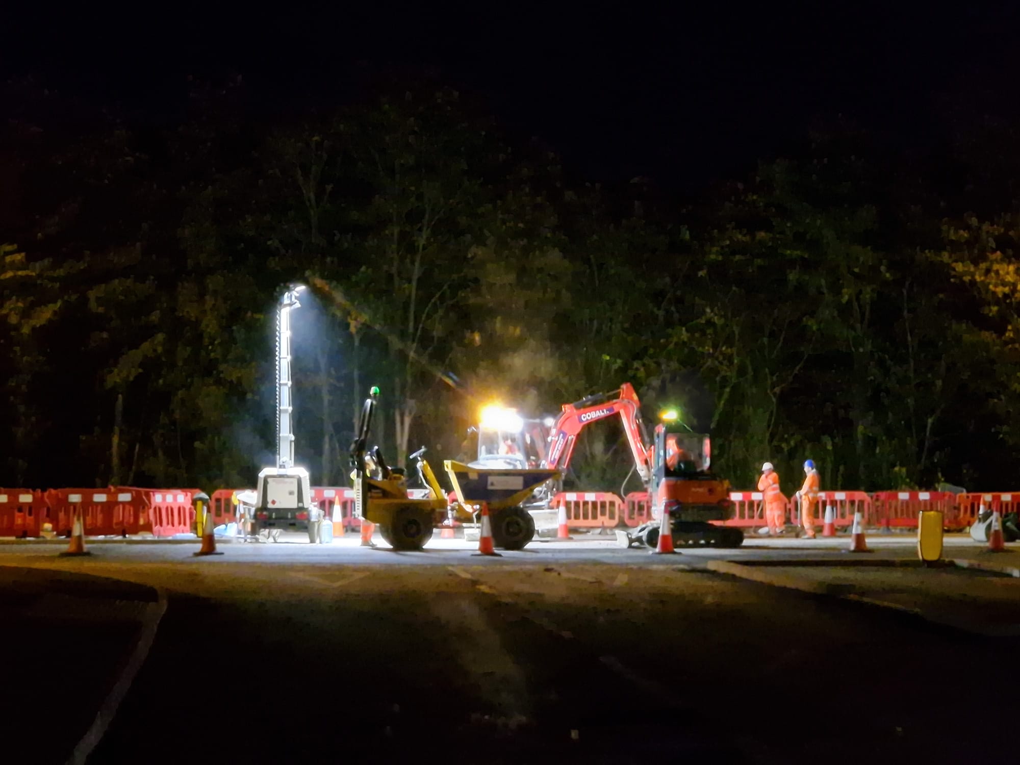Barriered night works zone lit by high-powered lighting with machinery in use