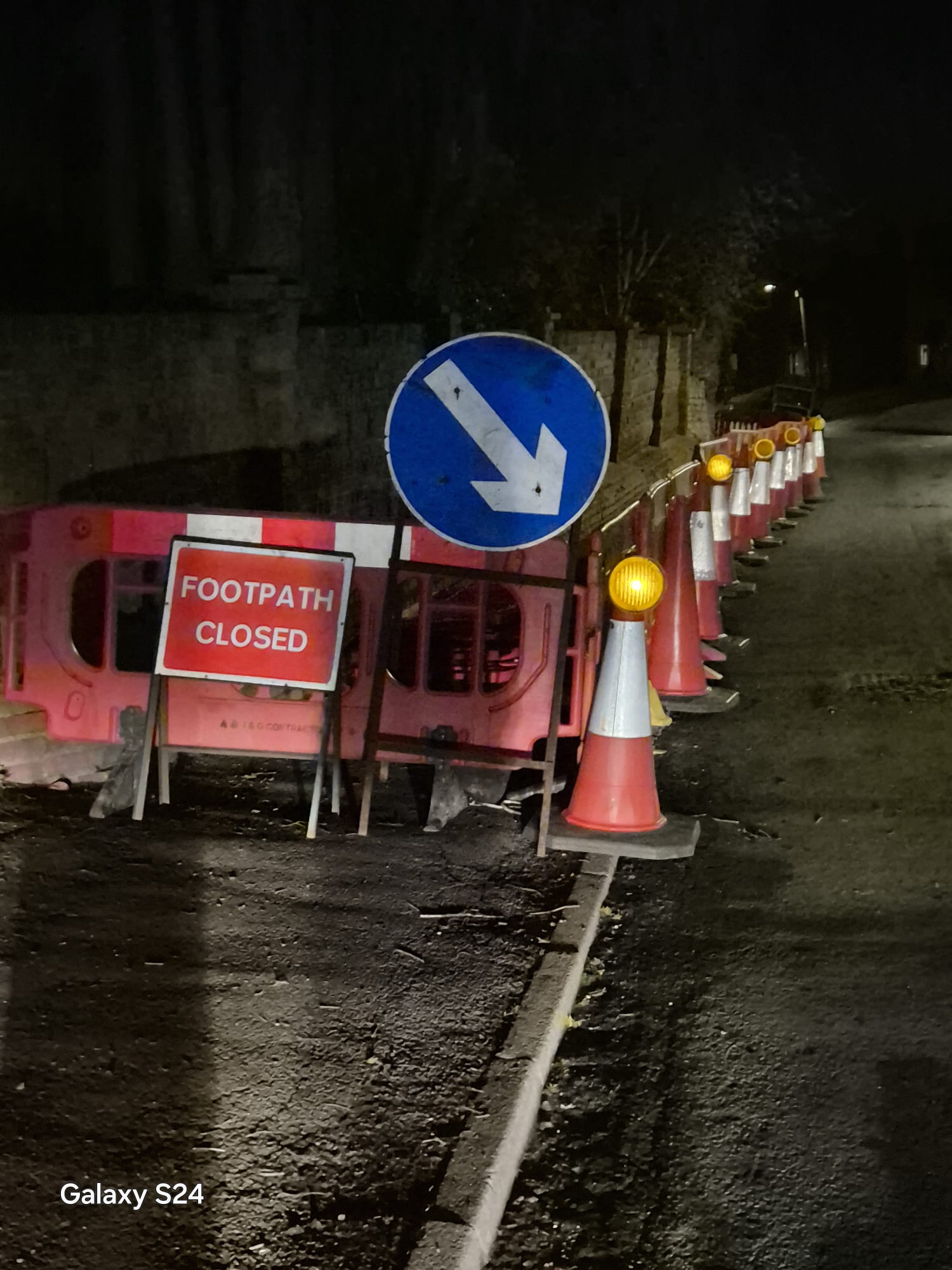 Footpath closed sign, keep-left arrow and lit cone taper on a night works scheme