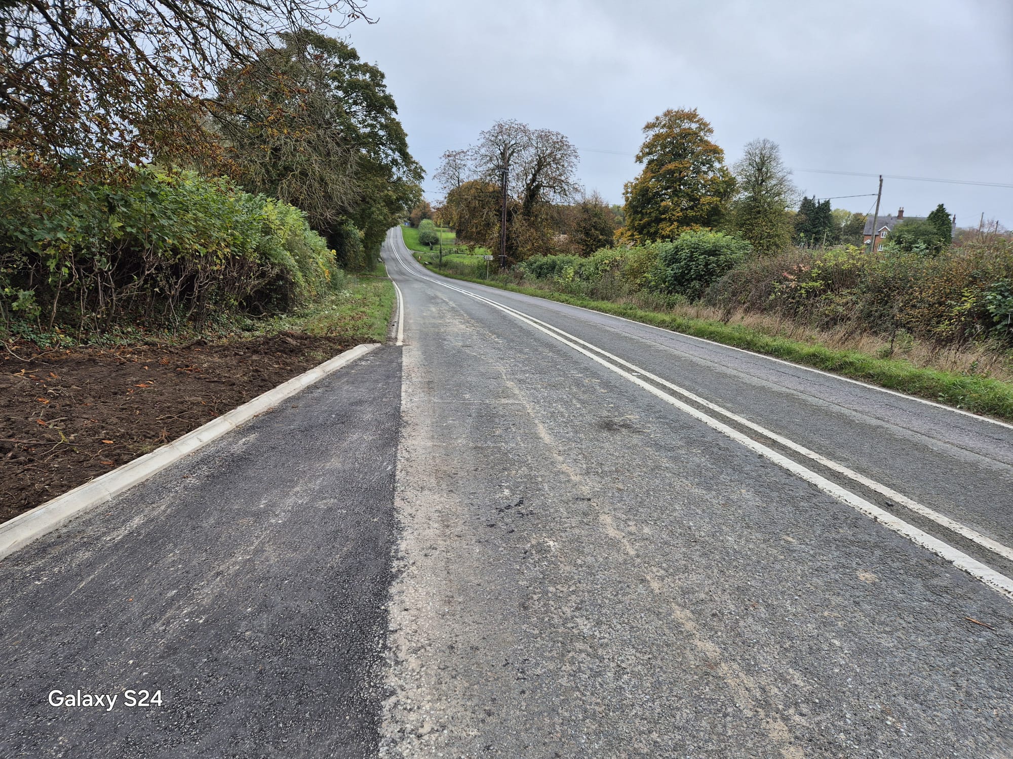 Completed rural road widening with new kerb line and surfacing after traffic management was removed