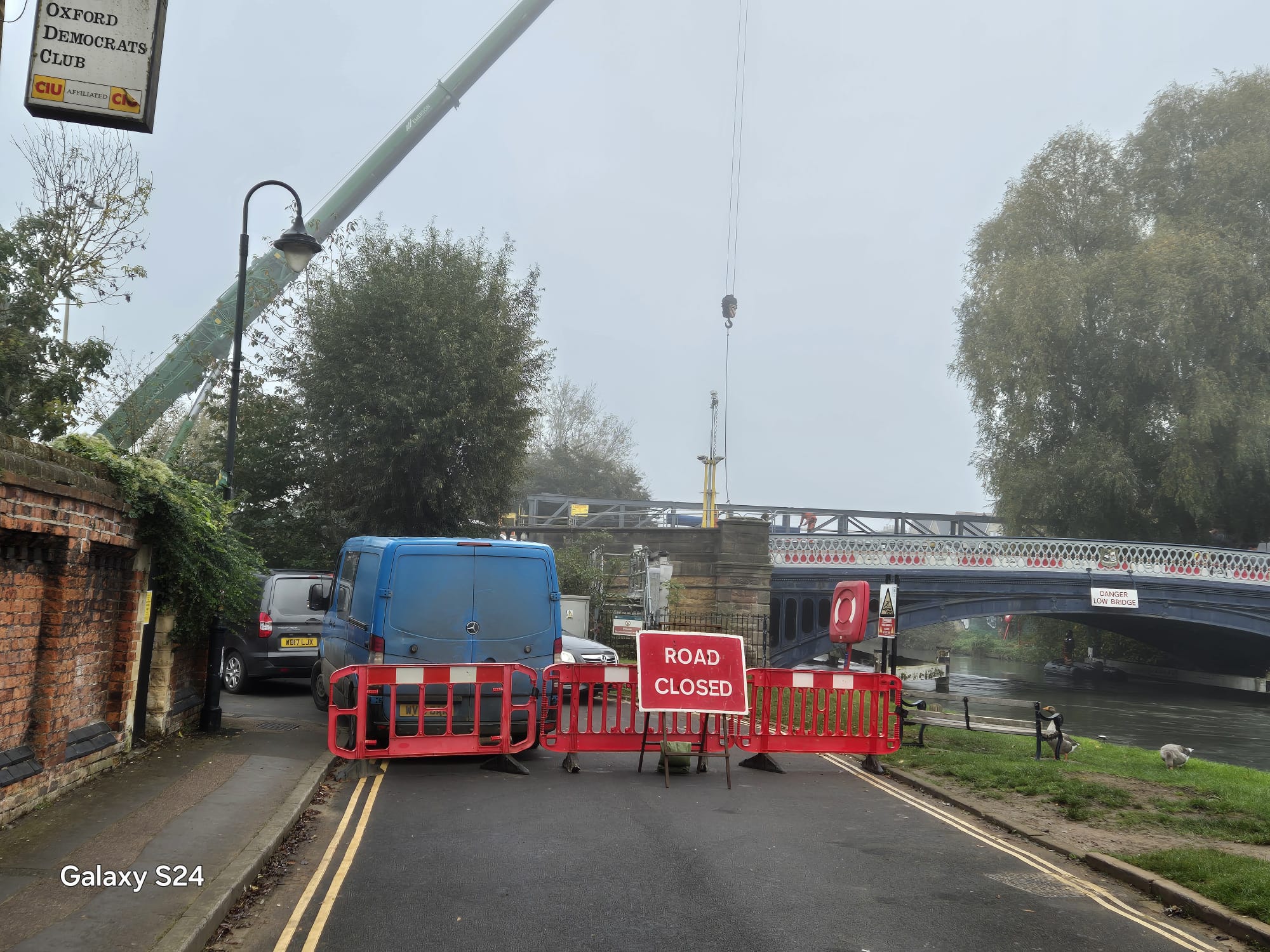Road closure barriers and works vehicle at a riverside construction site