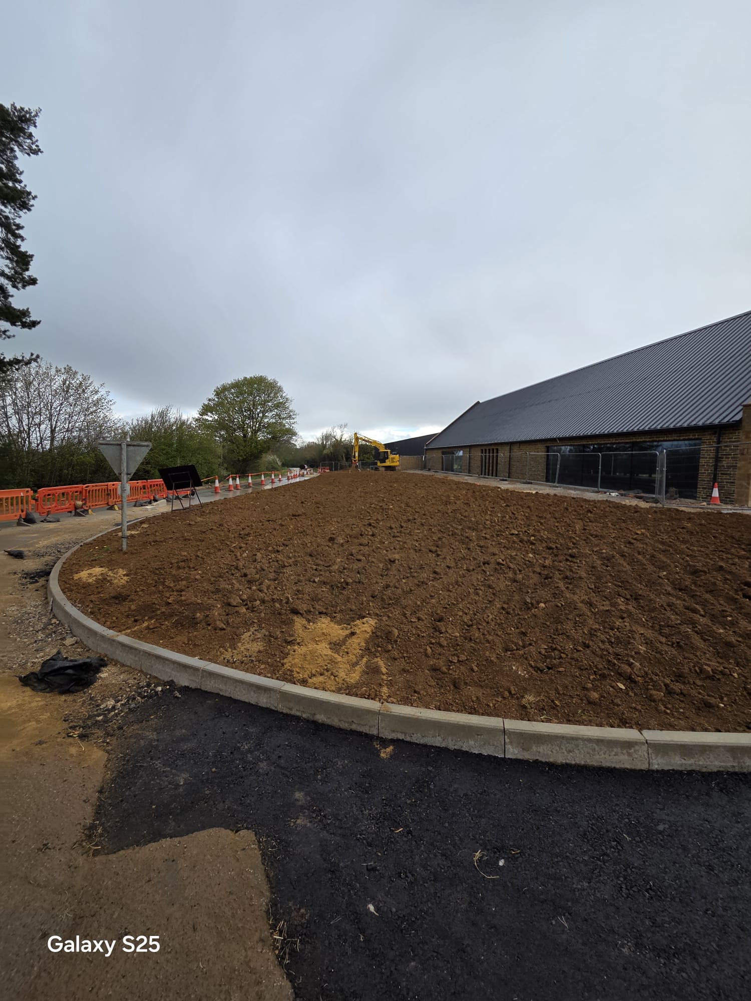 Newly kerbed construction site access with site fencing in the background
