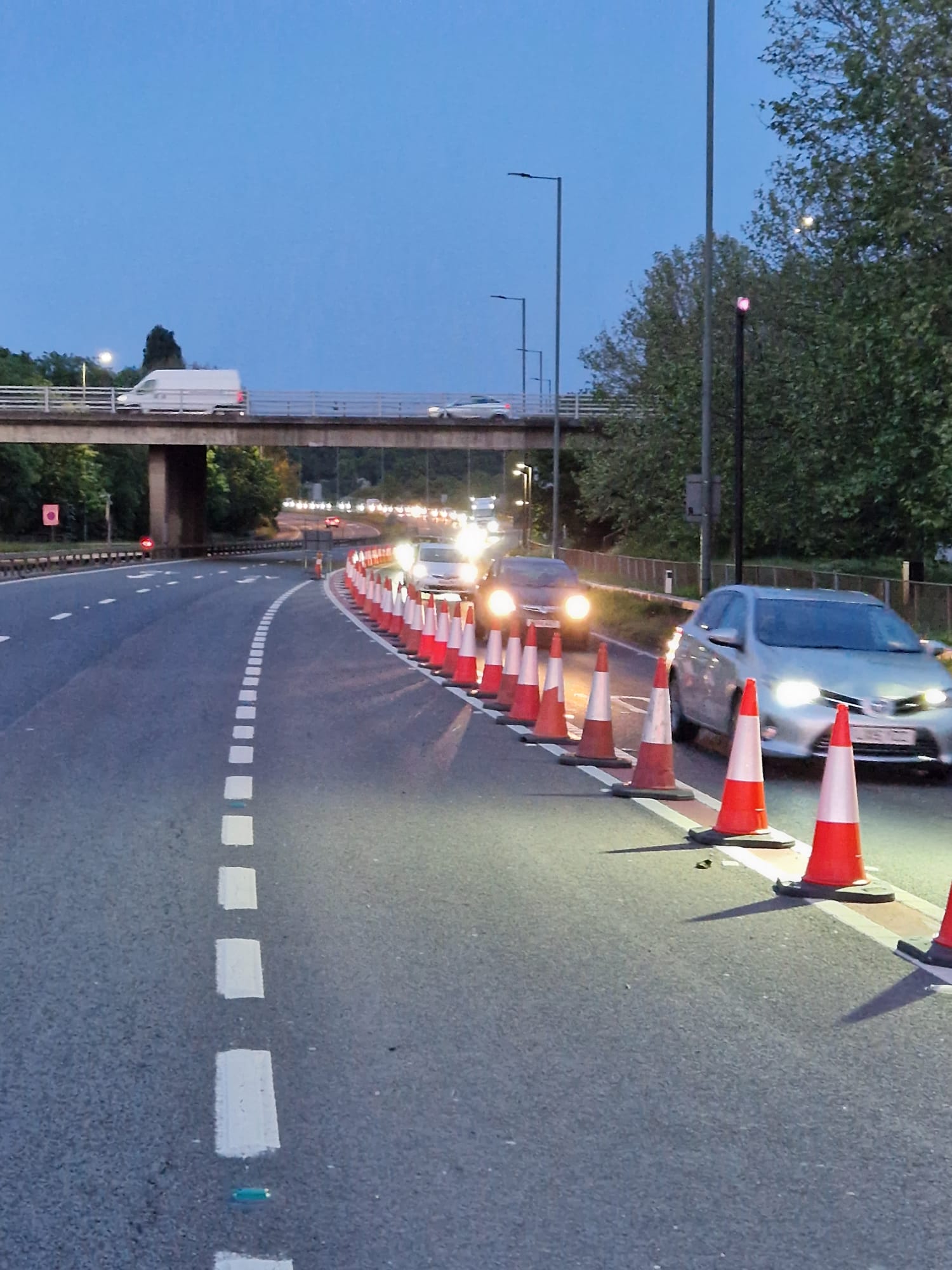 Coned taper forming a lane closure on a dual carriageway at dusk