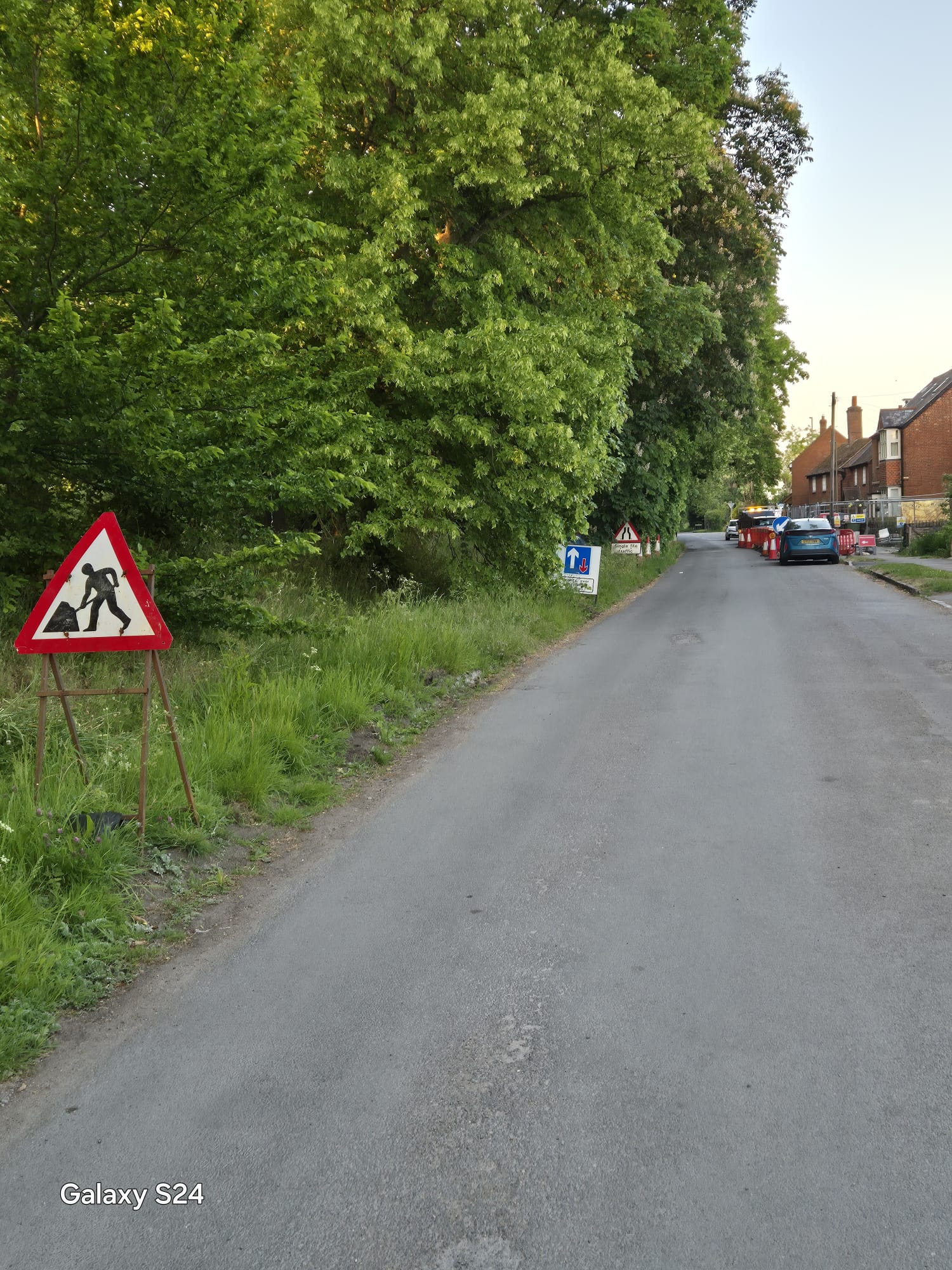 Priority and single file traffic signs guiding drivers towards a coned village works site