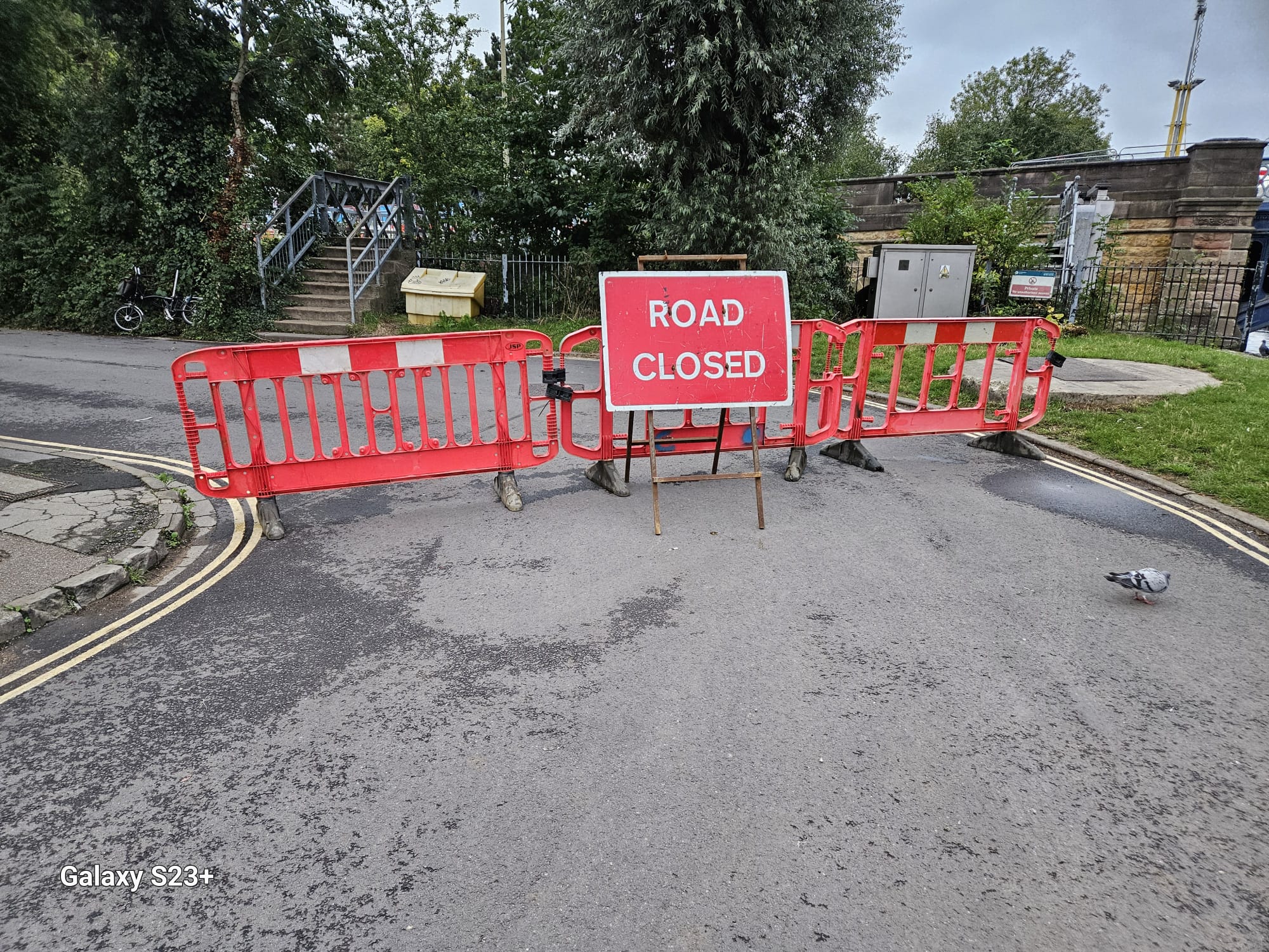 Road closed sign mounted on red barriers closing a paved road