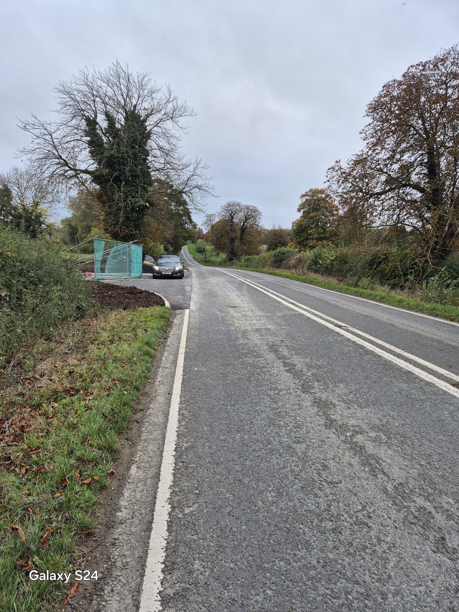 View along a rural carriageway towards a newly built and fenced site access
