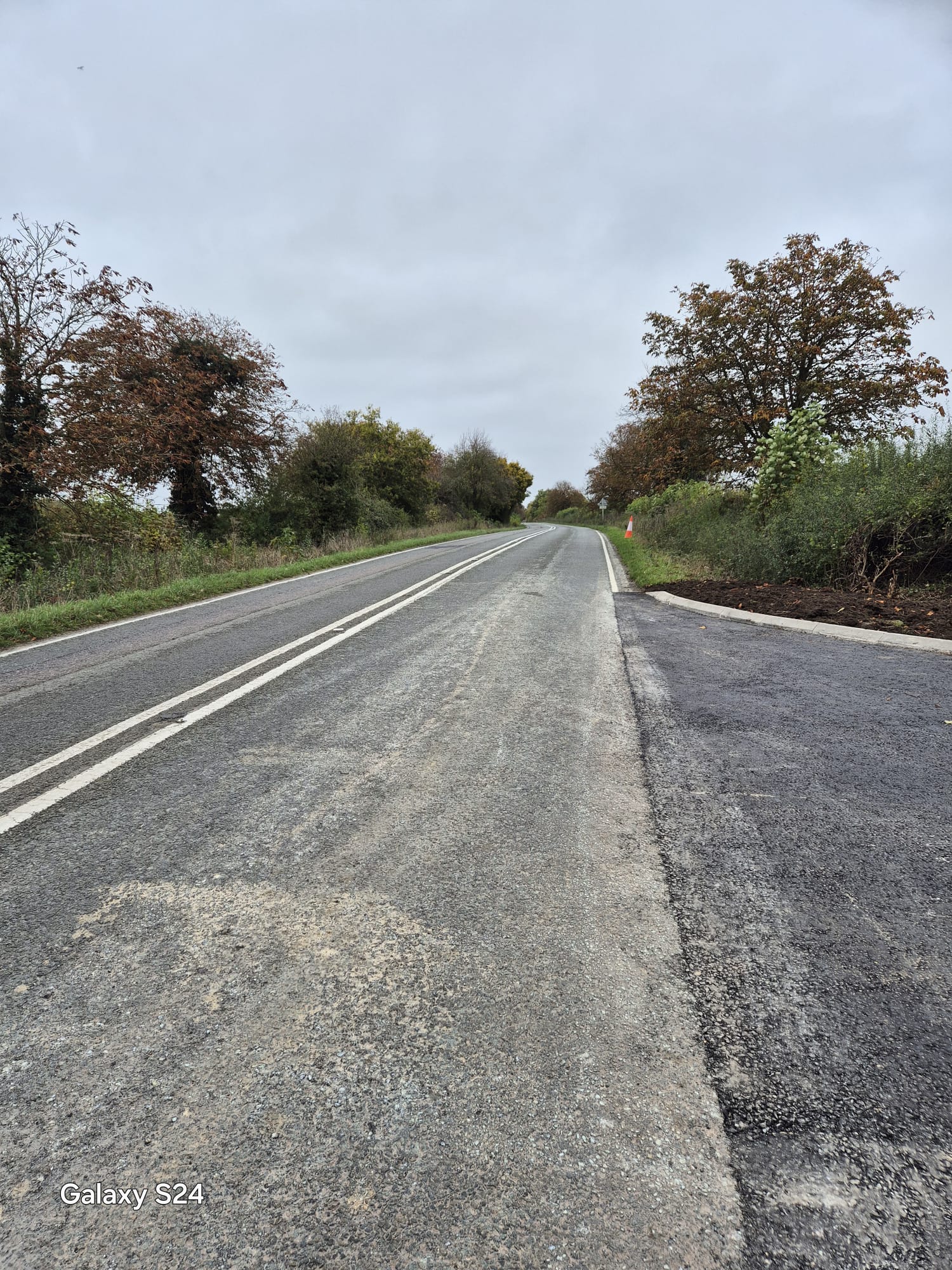 Newly surfaced site access bellmouth joining a rural carriageway with fresh road markings