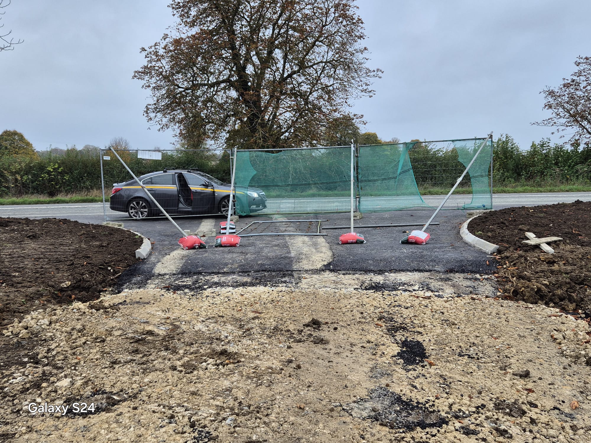 Fenced site entrance with a highway maintenance vehicle parked on the newly formed access