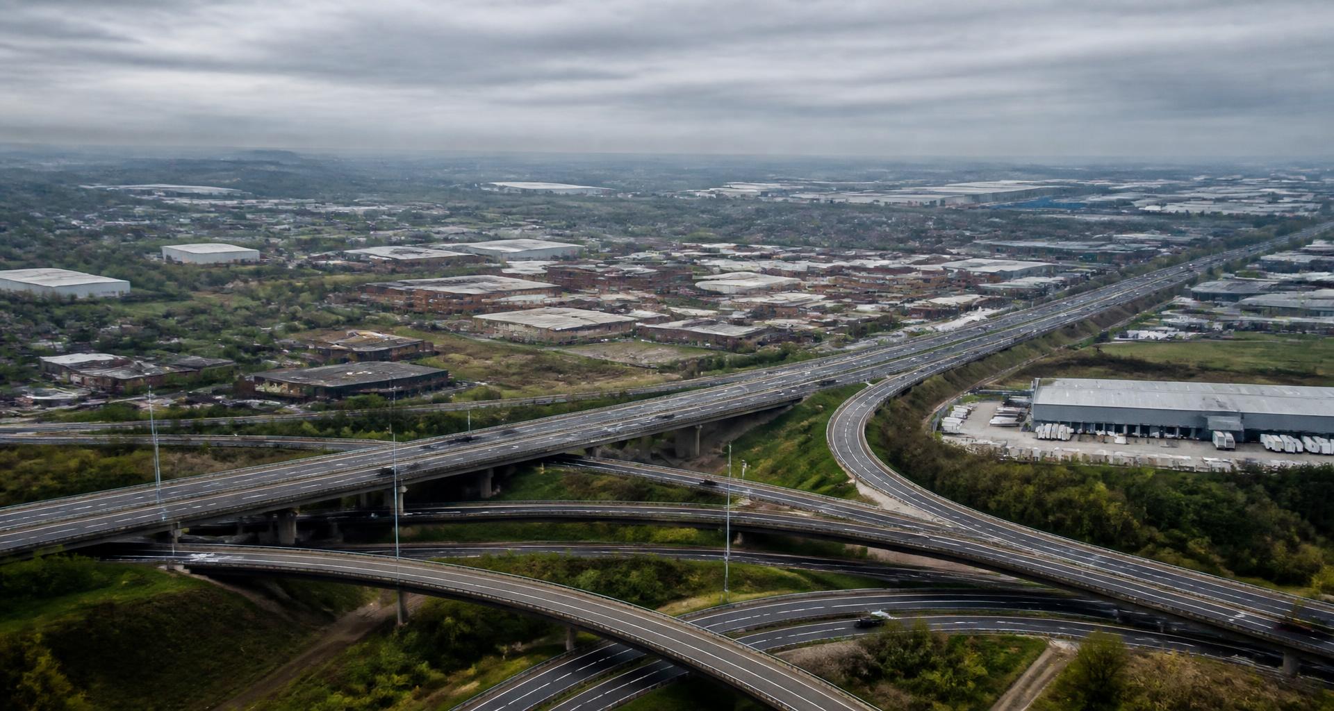 Midlands motorway interchange with sweeping slip roads and distribution warehouses beyond